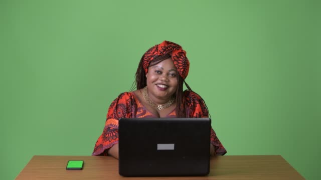 Schöne-afrikanische-Frau-in-traditioneller-Kleidung-vor-grünem-Hintergrund-mit-Übergewicht