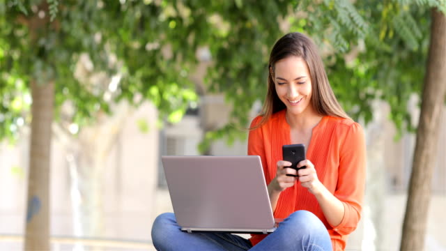 Mujer-usando-una-laptop-recibe-un-mensaje-de-teléfono