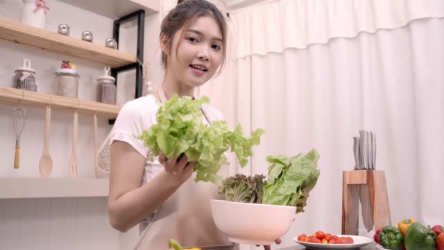 Mujer-asiática-blogger-usando-cámara-de-grabación-cómo-hacer-comida-sana-ensalada-video-para-su-abonado,-verduras-orgánicas-de-uso-femenino-preparar-ensalada-para-cuerpo-en-forma-en-casa.-Concepto-de-comida-sana.