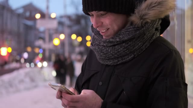 Man-typing-text-message-on-his-mobile-phone-in-winter