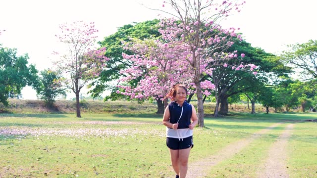 Eine-fette-asiatische-Frau,-die-morgens-im-natürlichen-Sonnenlicht-joggt.
Sie-versucht,-mit-Übung-Gewicht-zu-verlieren.--Konzept-Gesundheit-mit-Bewegung.-Zeitlupe