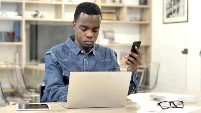 Hombre-africano-usando-smartphone-y-Laptop