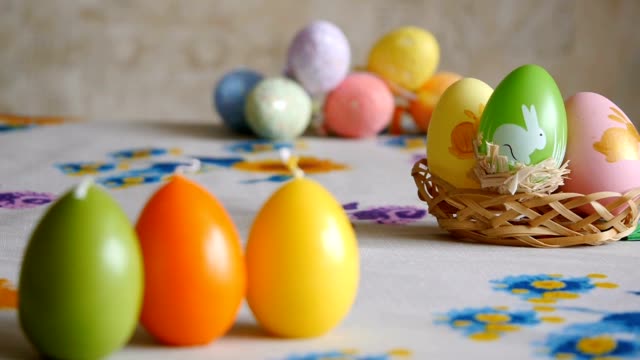 Velas-hechas-en-forma-de-huevo-de-Pascua.-Verde,-naranja,-amarillo.-Huevos-de-Pascua-velas-y-coloridos-huevos-de-Pascua-en-el-fondo.