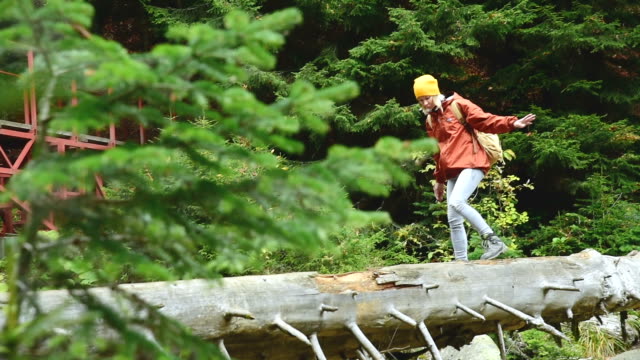 Slender-girl-walking-along-a-log-through-a-mountain-river-in-the-forest