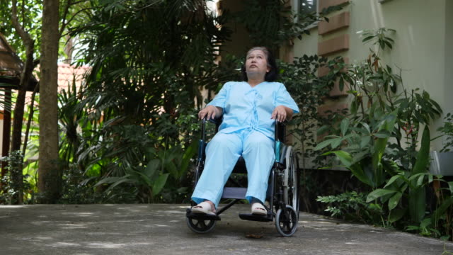 Behinderte-Seniorin-sitzt-auf-Rollstuhl-im-Krankenhauspark