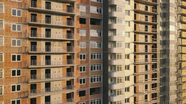 Aerial-view-of-the-facade-of-a-residential-apartment-building-under-construction.-High-rise-building-with-windows-and-balconies.-Construction-industry.-Urbanization