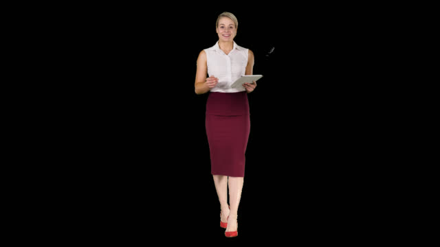 Smiling-businesswoman-using-electronic-tab-swiping-and-looking-to-the-camera-while-walking,-Alpha-Channel