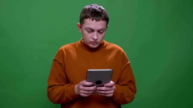 Nahaufnahme-von-jungen-attraktiven-kaukasischen-Männlichen-mit-der-Tablette-mit-Hintergrund-isoliert-auf-grün