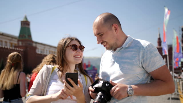 Happy-couple-tourists-walking-in-Moscow's-red-square,-admire-and-take-pictures.