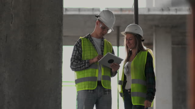 Engineers-or-architects-have-a-discussion-at-construction-site-looking-through-the-plan-of-construction.-contre-jour.-Engineers-or-architects-have-a-discussion.