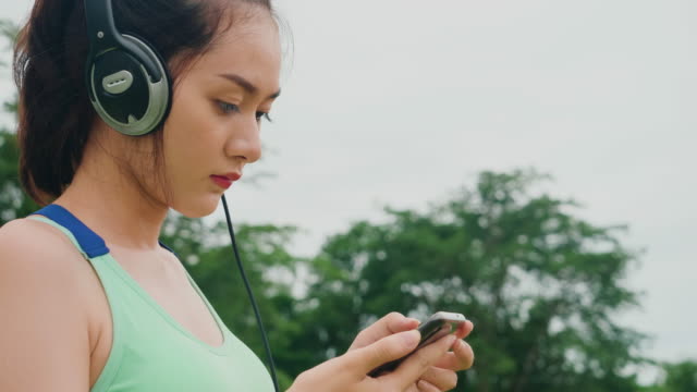 Estilo-de-vida-asiático-deporte-mujeres-sosteniendo-teléfono-inteligente-reproducir-música-relajación