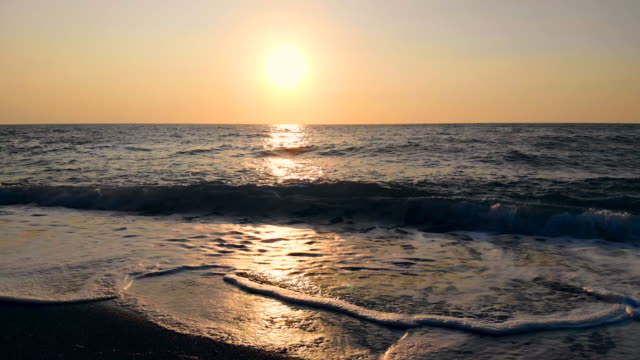 Meereswellen-und-ein-Strand-auf-einem-Sonnenuntergang-Hintergrund.