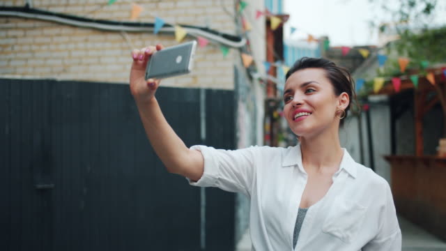 Zeitlupe-der-hübschen-Dame,-die-Selfie-draußen-mit-Smartphone-winken-Hand