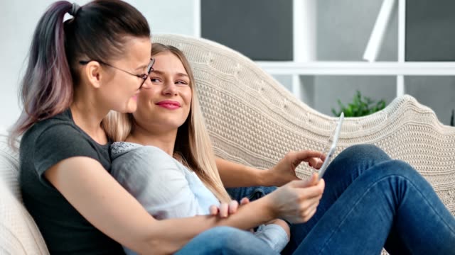 Charming-female-same-sex-couple-relaxing-together-having-tenderness-using-tablet-pc