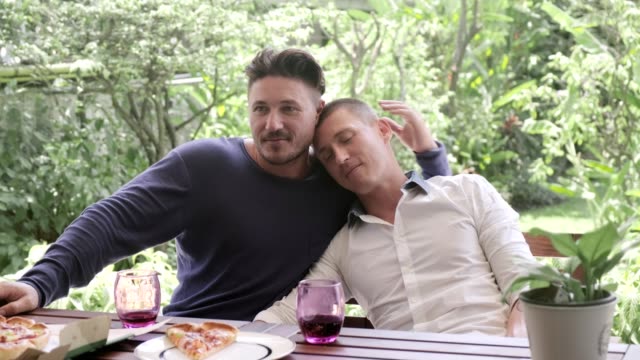 Gay-couple-having-pizza-for-lunch.-Hugging.