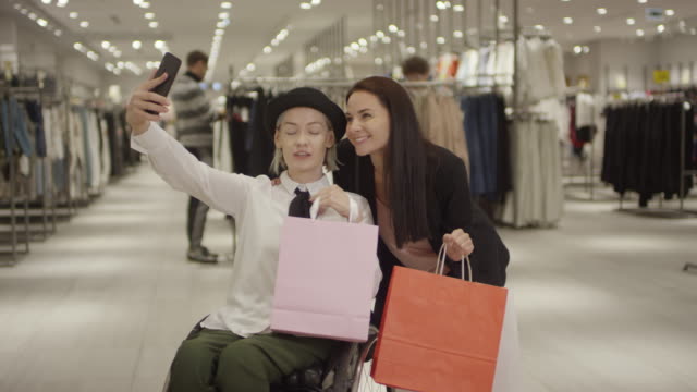 Mujer-en-silla-de-ruedas-tomando-selfie-con-amigo-después-de-ir-de-compras