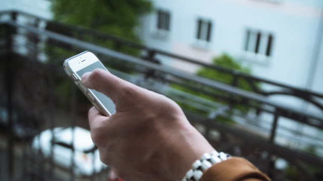Male-Hand-Using-Mobile-Phone-on-Balcony