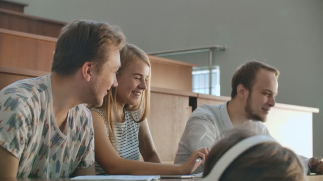 Drei-Studenten-Männer-und-Frauen-lachen-über-die-Pause-zwischen-den-Vorlesungen-sitzen-an-der-Universität
