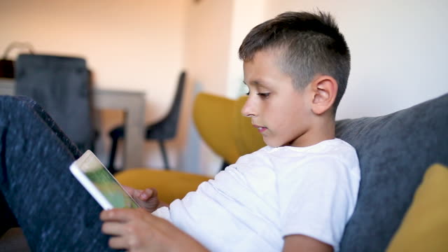 Young-boy-is-playing-games-on-his-tablet-at-home