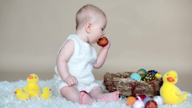 Süßes-kleinkind-Baby-junge,-spielen-mit-bunten-Ostereier-und-kleine-dekorative-Enten,-isolierte-Schuss,-beige-Hintergrund