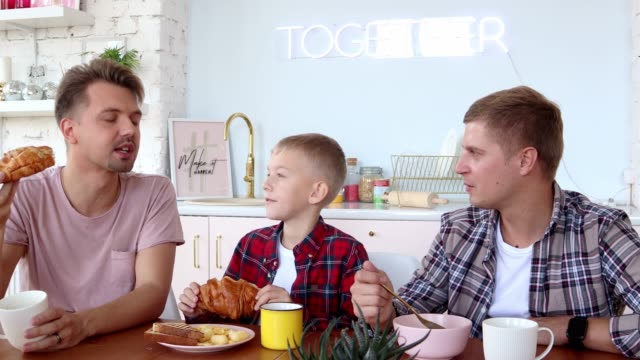 Happy-gay-family-two-fathers-and-son-are-having-breakfast-in-the-kitchen.