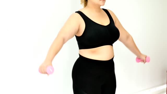 Mujer-joven-con-sobrepeso-en-ropa-deportiva-haciendo-ejercicio-para-bajar-de-peso-en-casa