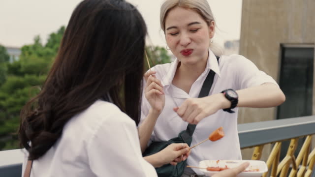 Asian-lesbian-couple-enjoying-traveling-in-Thailand-and-eating-meatball-having-fun-during-vacation-time.-LGBT-concept.