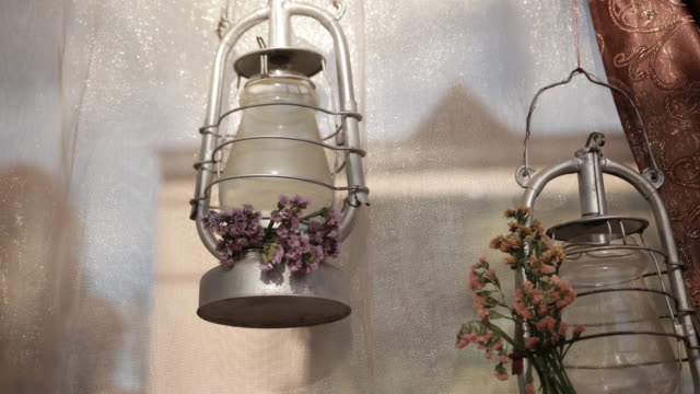 two-metal-silver-lamps-hanging-on-shiny-tulle-near-brown-curtain