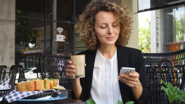 Joven-empresada-usando-smartphone-y-bebiendo-café