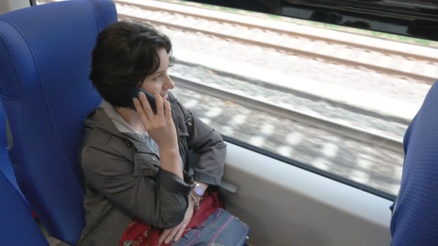 a-woman-is-sitting-on-a-train-talking-on-the-phone-side-view-from-above