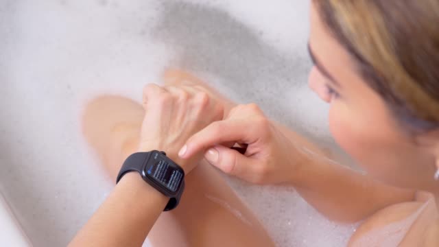 Atractiva-mujer-atleta-usando-y-usando-reloj-inteligente-en-el-baño.-Toque-de-la-pantalla-del-dispositivo-de-reloj-inteligente.