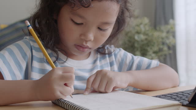 Asiatische-kleine-Mädchen-machen-Hausaufgaben-und-lernen-online-über-Internet-Kommunikation-auf-einem-Tablet-zu-Hause.-Nahaufnahme-des-Kindergesichts