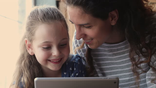 Closeup-view-mom-and-kid-having-fun-using-tablet