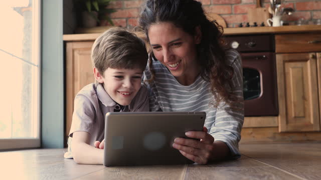 Mutter-Sohn-mit-Tablet-beobachten-Videos-lachen-dliegt-auf-dem-Boden