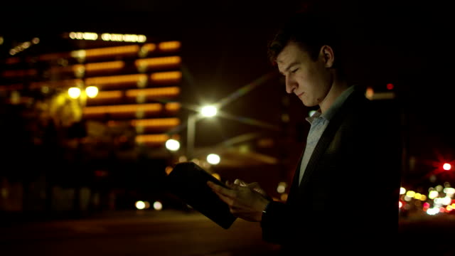 Junge-Touristen-nutzt-seinen-Tablettcomputer-auf-einer-Straße-in-der-Nacht