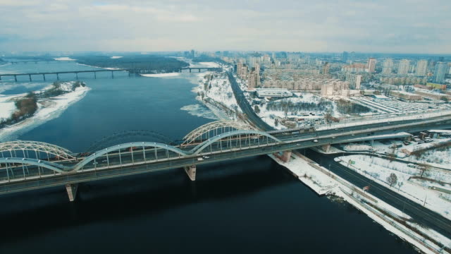 Cars-and-train-moves-on-a-bridge-over-a-frozen-river-aerial-drone-footage