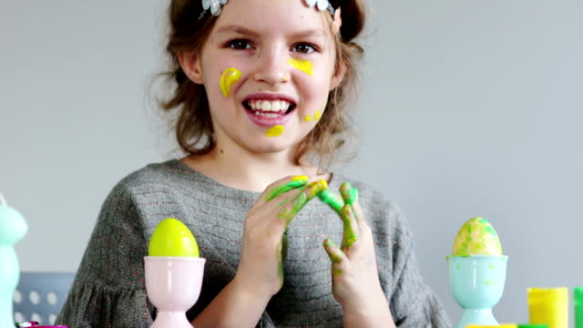 Cute-little-girl-painting-colorful-easter-eggs.-She-dirty-her-hands-and-face