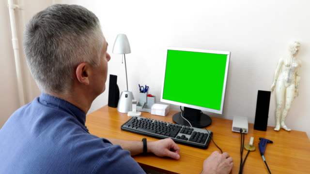 Arzt-sitzt-am-Computer-mit-einem-green-screen