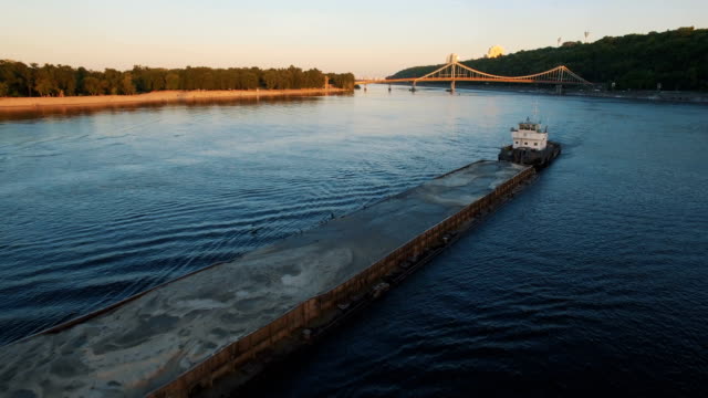 Barge-sails-along-the-river-near-the-city-port-on-sunset-aerial-footage