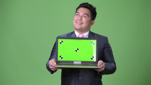 Young-handsome-overweight-Asian-businessman-against-green-background
