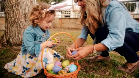 Little-girl-with-grandmother-enjoying-Easter-egg-hunt-in-garden