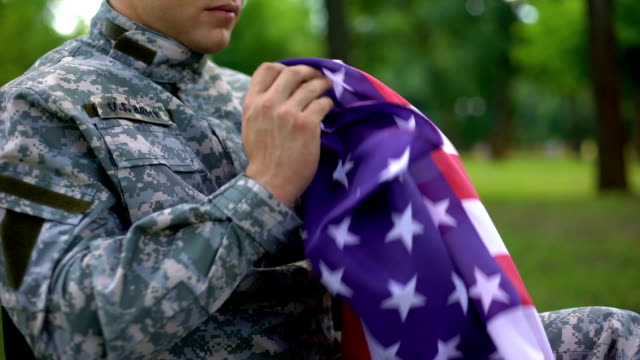 Herido-a-soldado-americano-con-una-bandera-nacional-en-el-pensamiento-de-las-manos-de-guerra,-recuerdos