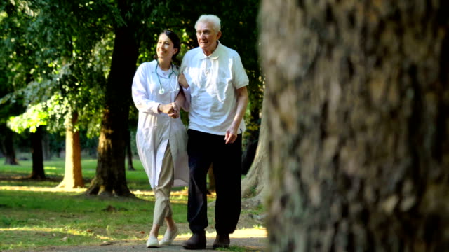 Doctor,-nurse,-care-for-the-elderly,-girl-(woman)-and-grandfather-sitting,-walking-in-the-park-in-the-fresh-air.