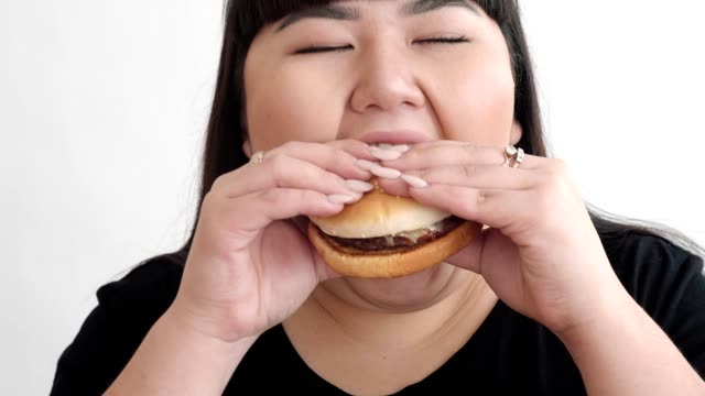 la-chica-de-aspecto-asiático-come-una-hamburguesa-y-disfruta-el-sabor.-no-una-dieta-saludable-para-los-jóvenes