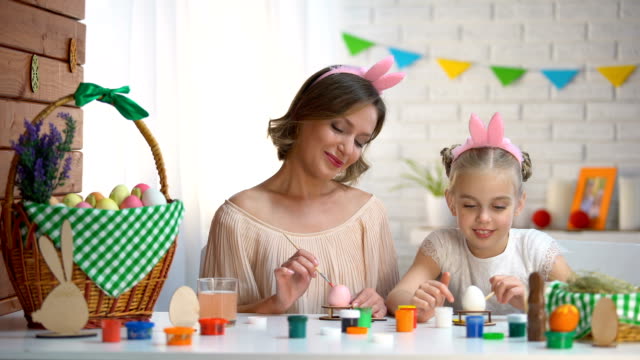 Daughter-and-mother-in-cute-headbands-having-fun-painting-nose-to-each-other
