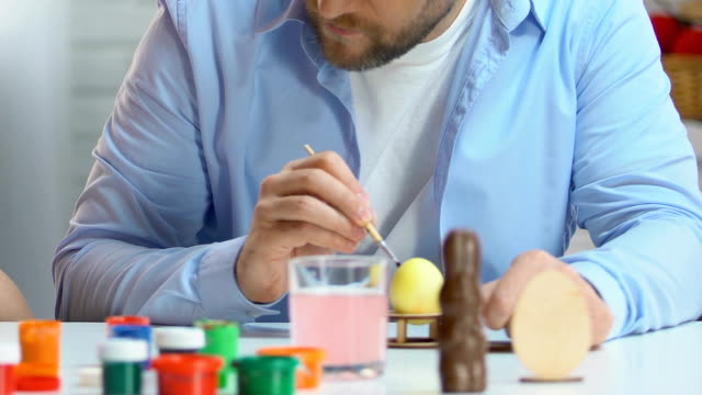 Father-and-daughter-preparing-for-Easter,-drawing-eggs-with-colorful-paints