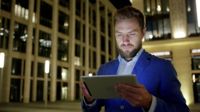 Mittleren-Erwachsenen-Geschäftsmann-in-Nacht-Straße-steht-und-Anwendung-auf-dem-Tablet-PC