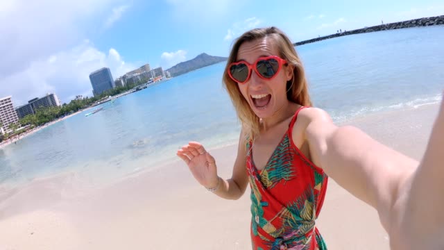 Selfie-von-Mädchen-mit-Herz-geformt-Sonnenbrille-am-Strand-von-Hawaii.-Junge-Frau,-die-eine-Selfie-am-Strand-von-Waikiki-in-Honolulu.-Hawaii-USA