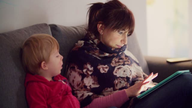 madre-con-su-hijo-usando-tableta-en-el-sofá-en-casa
