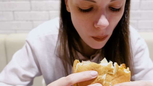 Frau-isst-einen-Hamburger-mit-Genuss-und-Freude-im-Café.